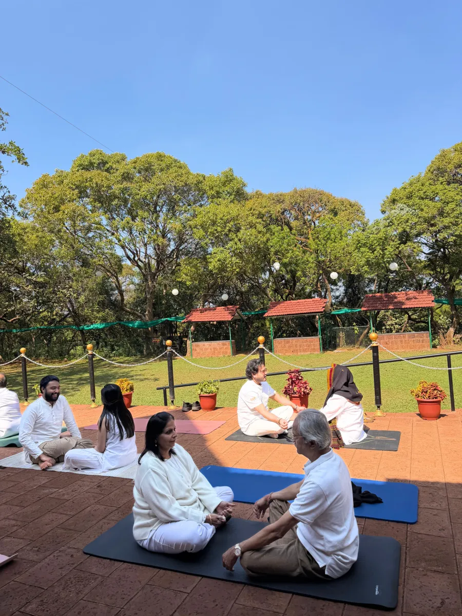 Participants practising seated yoga on mats on the brick terrace of the club