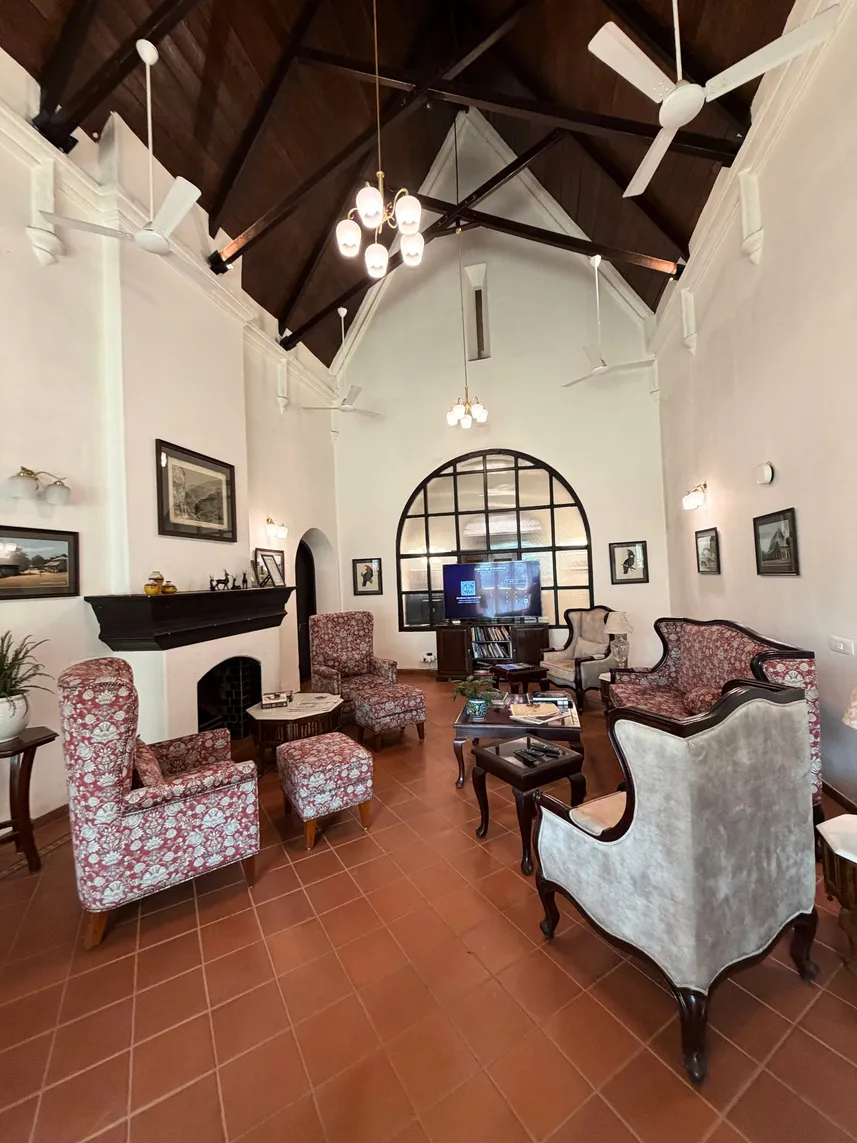 The club lounge with a fireplace, floral armchairs and an arched window