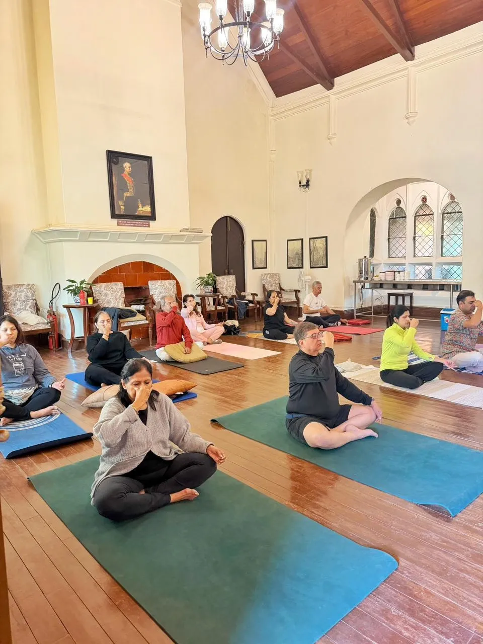 The group practising prāṇāyāma together in the wood-floored hall of the club